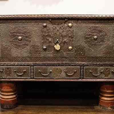 Wedding chest with red feet: The teakwood chest, adorned with brass, has intricate patterns and a sturdy lock.