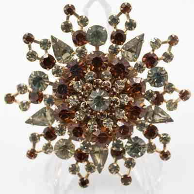 Topaz sunburst brooch that belonged to Mrs. Jessie Jordan.: Up close image of the large brooch, it is encrusted with two different colors of topaz arranged in a sunburst pattern.