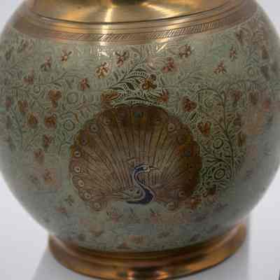 Peacock urns: The brass urn features intricate blue peacock designs and floral patterns on its rounded surface.