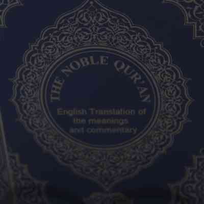 Close up of “The Noble Quran”: An Islamic ornamental design surrounds the title “The Noble Quran; English Translation of the meanings and commentary.”