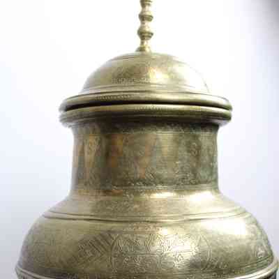 Large brass urn: A large brass urn features intricate engraved patterns on its surface and lid.