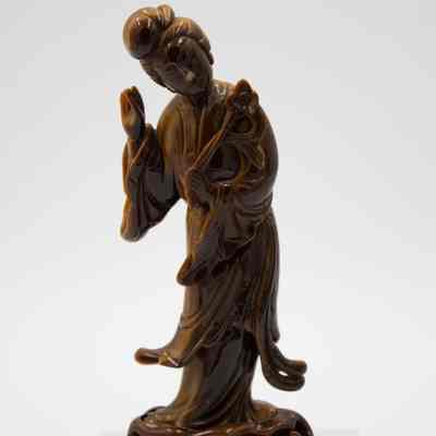 Carved Tiger's Eye Guanyin figurine.: Image of the yellow-brown carved Tiger's Eye figurine depicted Guanyin holding a lotus flower.