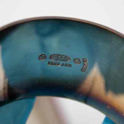 Inside of one of the silver napkin rings.: Up close image of the inside of the napkin rings. They are stamped with maker's marks and "ENGLAND." There is a "B," "S," and "EPNS."