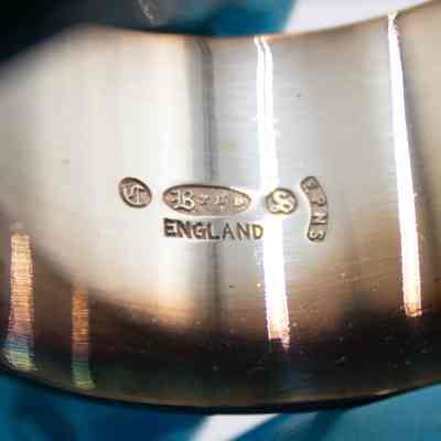 Inside of one of the silver napkin rings.: Up close image of the inside of the napkin rings. They are stamped with maker's marks and "ENGLAND." There is a "B," "S," and "EPNS."