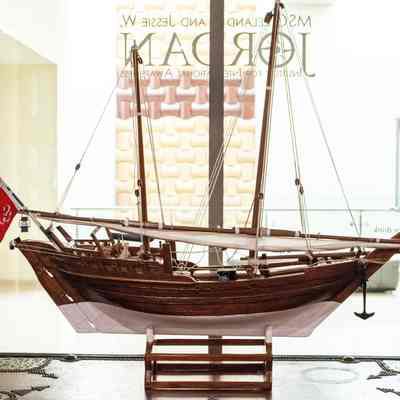 Model Dhow: The image shows a detailed model of a traditional wooden boat with red flag accents.