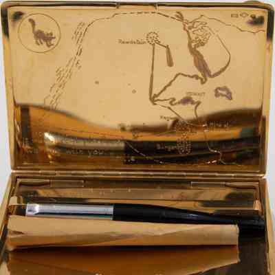 Cigarette case: The image shows a gold case with an engraved map and a cigarette inside it.