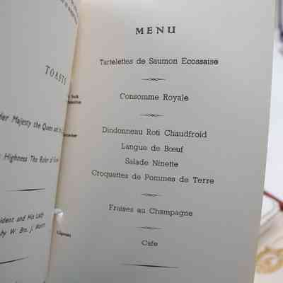 Inside the program from a Ladies' Night at the Rowland Chadwick Masonic Lodge, showing the menu page.: Up close image of the menu on the inside of the program. The pages are an off-white with black text. The menu lists food from the Ladies' Night, "Tartelettes de Saumon Ecossaie," "Consomme Royale," "Dindonneau Roti Chaudfroid," "Langue de Boeuf," "Salade Ninette," "Croquettes de Pommes de Terre," "Fraises au Champagne," and "Cafe." It also lists the "Director of Ceremonies" as "W. Bro. J. Martin" at the bottom.