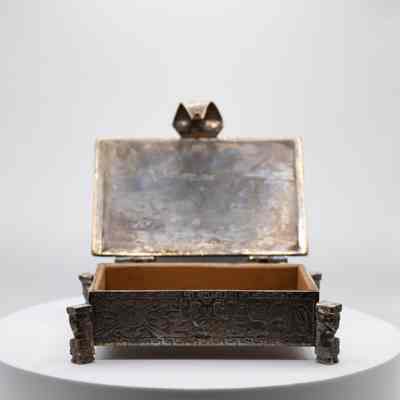 Cigarette box: The image shows a decorative silver Incan-style cigarette box, intricately engraved with mythological art.