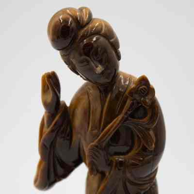 Carved Tiger's Eye Guanyin figurine.: Up close image of the yellow-brown carved Tiger's Eye figurine depicted Guanyin holding a lotus flower.
