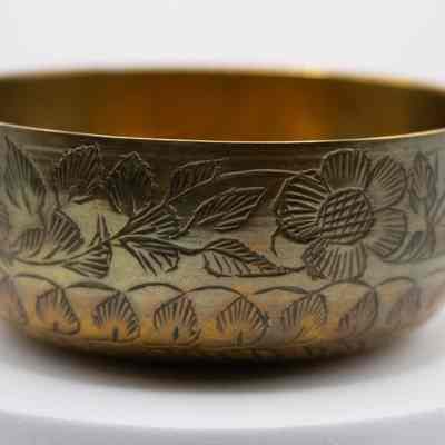 Brass finger bowl with engraved floral and leaf design: A small bowl with engraved flowers and leaves.