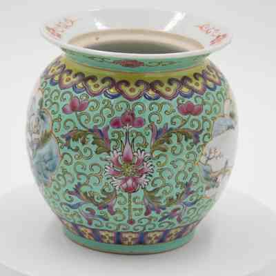Side of the mint green porcelain jar.: Image of the side of the mint green porcelain jar. It is decorated with green swirls, purple and blue details, and a pink flower.