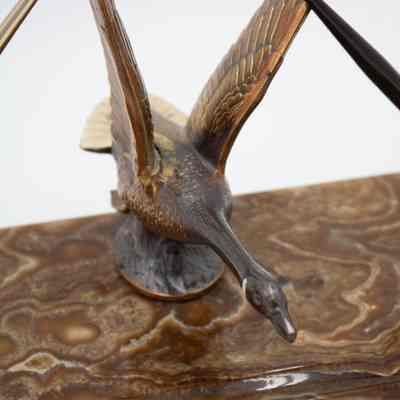 Close up of duck: A bronze duck sculpture on a marble base features detailed, outstretched wings and a nameplate below