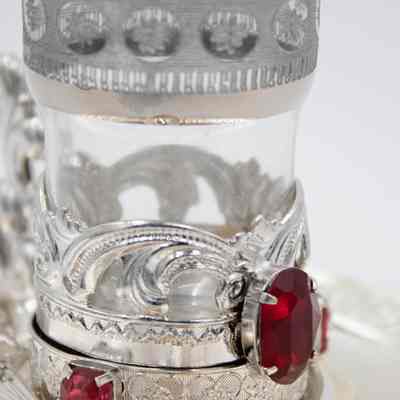 Glass and plated silver teacup.: Up close image on the glass and plated silver teacup with red gemstones. The glass is etched with a small flower design.