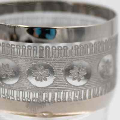 Etched design in the glass teacup.: Up close image of the etched design on the glass teacup. The design has small flowers and the rim of the glass is also silver plated.