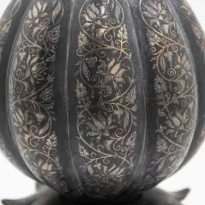 Top of the burnished metal tulip-shaped stemmed vase.: Up close image of the tulip-shaped goblet engraved with flower motifs.