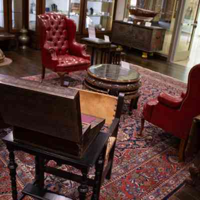 Red and blue area rug: The room features a large red and blue area rug with cream inner corners, complementing elegant red chairs and wooden furniture.