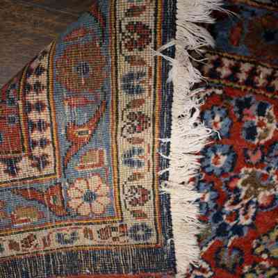 Red and blue area rug: The image shows a richly patterned red and blue area rug, partly flipped up.