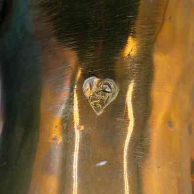 Engraving on brass coffee urn: A close-up image displays a brass coffee urn with reflective surfaces and a makers mark.