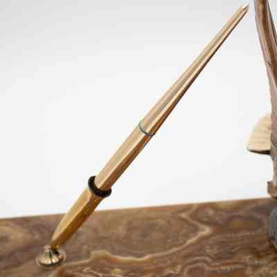 Pen holder: The image shows a gold pen resting in a holder on a brown, marble-patterned base.