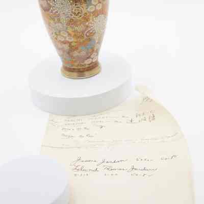 Japanese cloisonne floral vase given to the Jordans by Masanobu Tsuji with associated note.: Image of multicolored Cloisonné vase decorated with a floral pattern. There are white, red, blue, pink, and orange flowers on gold. The note is handwritten on yellowing paper.