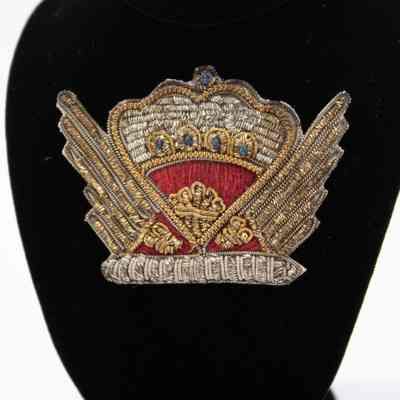 Crown pin: The red and silver crown pin, handmade in India, features intricate embroidery, symbolizing its regal presentation to Mrs. Jordan by Queen Elizabeth II.