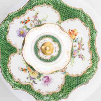 White and green inkwell: A white ceramic inkwell with gold and floral details on a decorative plate.