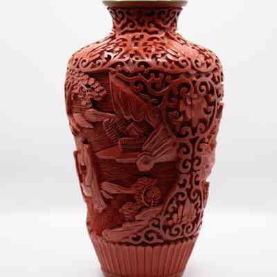 Cinnabar vase: The vase features intricate cinnabar carvings, showcasing detailed patterns and designs all over its surface.