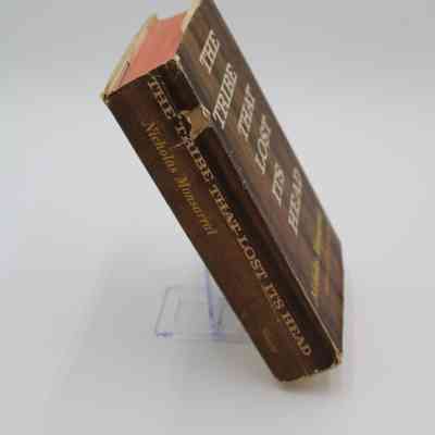 Book Spine: The book spine of “The Tribe That Lost its Head” features the book title, author name, and publisher. This angle also reveals that the book's pages have a red border. A portion of the spine is ripped, revealing that the hardcover is a light tan.