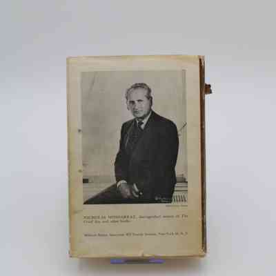 Back Cover: The back cover of “The Tribe That Lost its Head” features a black and white photograph of the author Nicholas Monsarrat sitting on a desk and facing the camera. Below him is the address of the book's publisher. The back is weathered and yellowed.