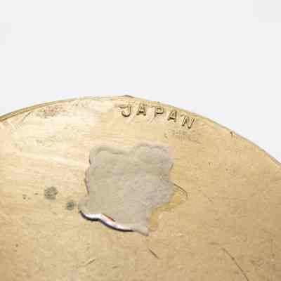 Bottom of the gold sleigh.: Up close image of the bottom of the gold sleigh. It is stamped with "JAPAN" and there are remnants of a sticker.
