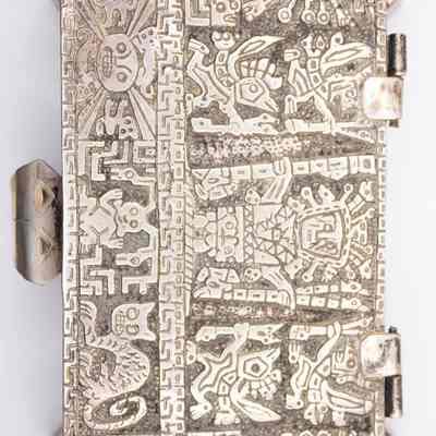 Cigarette box: The silver cigarette box features intricate Pre-Columbian, Incan-style mythological motifs.
