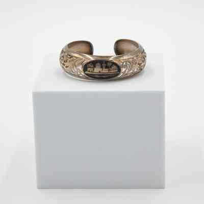 Silver cuff bracelet given to Mrs. Jessie Jordan by her husband, Mr. L.T. Jordan.: Image of the silver cuff bracelet with Arabesque carvings and small Arab-looking town scene. The cuff has a cut out leaf pattern.
