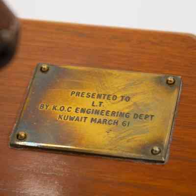 Brass Plaque: Close-up image of the brass plaque on the first book end. It reads "Presented to L.T. by K.O.C Engineering Dept Kuwait March 61."