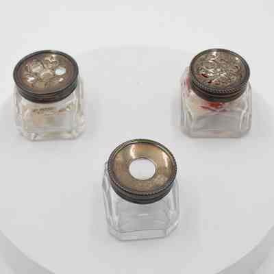 Three crystal ink bottles: The image shows three crystal ink bottles with ornate metal lids, each containing visible notes inside. Two bottles lids have geometric patterns and one is solid with a large open hole.