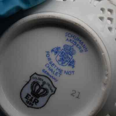 Bottom of forget-me-not dish: The white bottom of the dish has different logos and information, including, "21," "Schumann Arzberg; Forget Me Not Chalet; Germany," and, "Golden Crown, E&R, 1886,":
