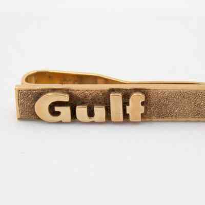 Golf "Gulf" tie bar: A thin rectangular tie bar with the word "Gulf" in thick, protruding text.