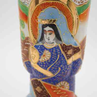 Woman on the painted Japanese porcelain vase.: Up close image of the painted Japanese porcelain vase. It is decorated with brown, green, orange, and blue paint and depicts a woman. The vase has a faux cloisonne look with raised gold paint.