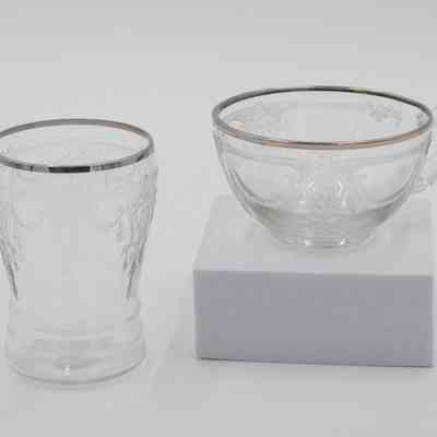 Tea cup and matching glass.: An etched clear glass cup and a matching tea cup are displayed. They have matching platinum rims and designs.