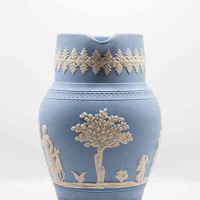 Wedgwood Jasperware pitcher: The Wedgwood blue Jasperware pitcher features intricate white relief designs. This side of the pitcher features a tree and a flower.