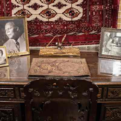 Wooden desk with decorations: The wooden desk has framed photos of Jessie and L.T. Jordan, a pen and pencil stand, a leather desk mat, and a silk rose in a vase.