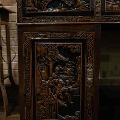 Decorative panels on wooden desk: The carved wooden Hong Kong desk showcases intricate designs, depicting detailed scenes and patterns.