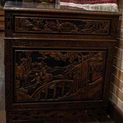 Decorative panels on wooden desk: The image shows an intricately carved wooden desk featuring detailed scenes and patterns.