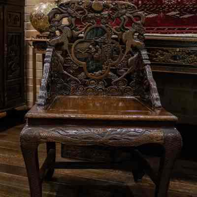 Wooden chair: The carved wooden chair from Hong Kong features intricate designs and rests on a polished hardwood floor.
