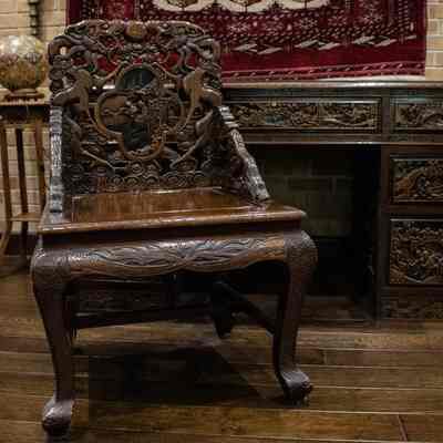 Wooden chair: The image shows intricately carved wooden desk and chair on a wooden floor, with artistic details.