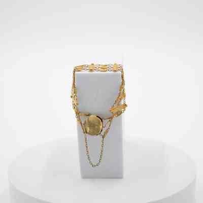 Gold bracelet with locket that belonged to Mrs. Jessie Jordan.: Image of the gold floral locket with three chains on a white box. The engraving on the back of the locket reads "J.L.W.J. January 1936."