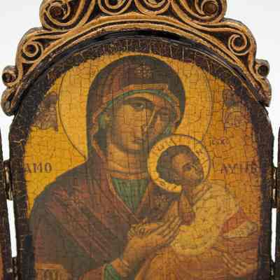 Center panel of triptcyh: Close up image of the triptych's center panel. It is a painted depiction of Madonna and Child. The Madonna has a cruciform halo and is holding the Child. Both are in traditional Byzantine dress. Next to the Child is "IX CX", which translates to "Jesus Christ" in Greek. The child has a cruciform halo with the Greek letters "ὁ ὤ v" which can roughly translate to "I am what I am." The painting is cracked and darkened.