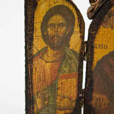 Left door of triptych: Close up image of the left door of the triptych. In the door is a Byzantine-style depiction of Jesus with a cruciform halo. He is holding the bible in his left hand while making the Greek letters "Chi Rho" with his other hand, a reference to Jesus' name in Greek. The paint is cracked and darkened.