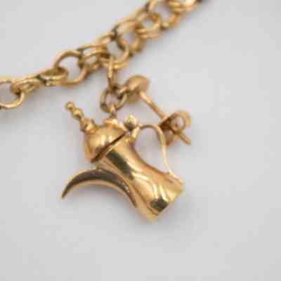 One of two gold coffee pots on Mrs. Jessie Jordan's gold charm bracelet.: Up close image of one of the gold Arabian-style coffee pots on the charm bracelet. The coffee pot was originally an earring and the screw back and post can be seen.