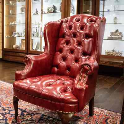 Red leather chair: A red, leather wingback chair with tufting and dark wooden feet.