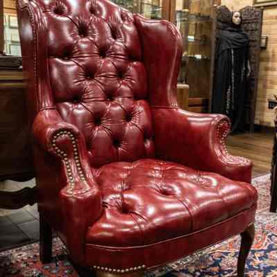 Red leather chair: A red, leather wingback chair with tufting and dark wooden feet.